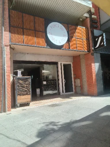 Fachada de Porco Dio con su rótulo circular y entrada a pie de calle en Lleida